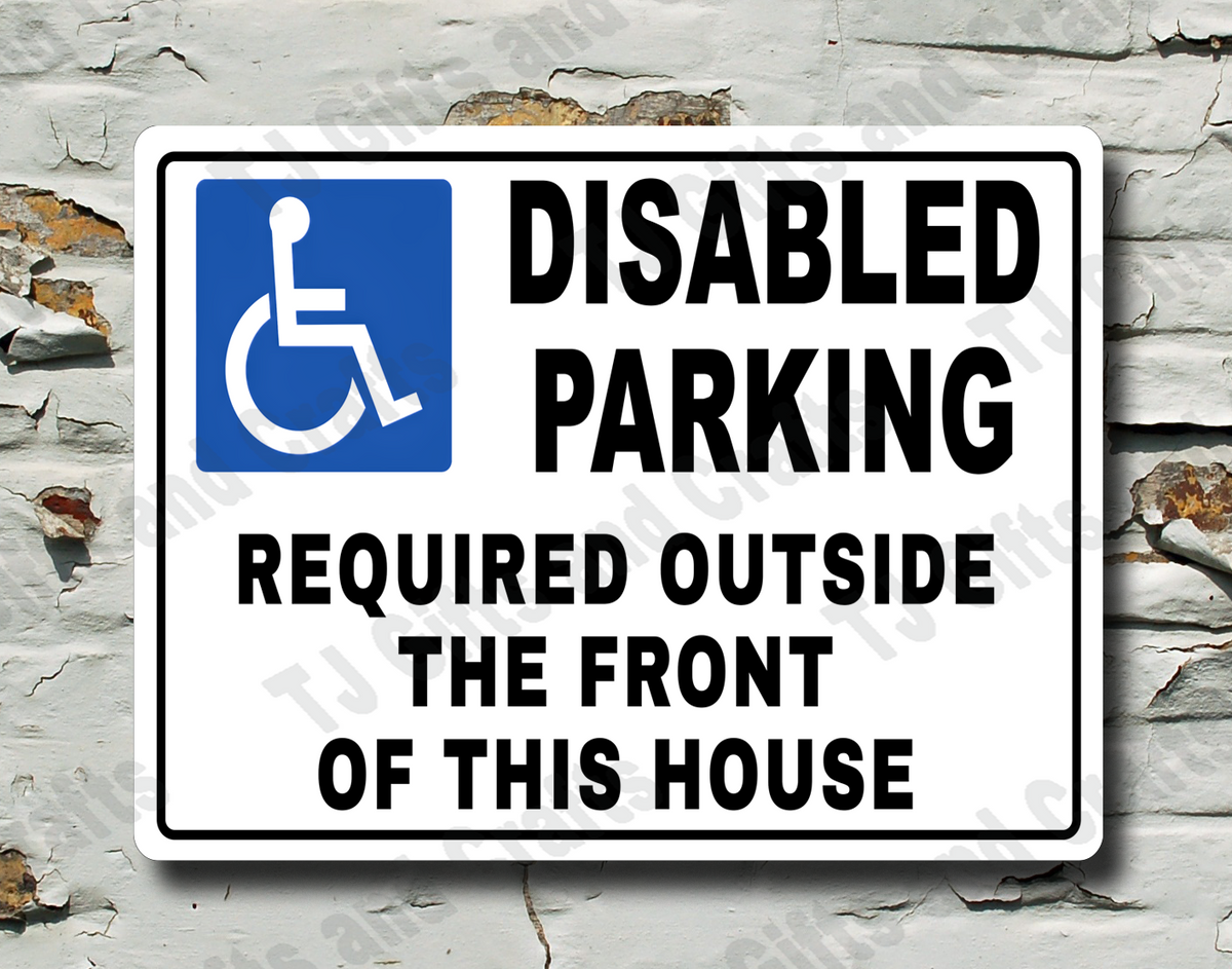 A white rectangular 'Disabled Parking Required Outside the Front of This House' sign with a blue wheelchair symbol, mounted on a distressed white brick wall.