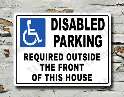 A white rectangular 'Disabled Parking Required Outside the Front of This House' sign with a blue wheelchair symbol, mounted on a distressed white brick wall.