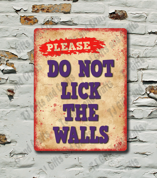 A rectangular vintage-style metal sign with a distressed beige background, red border, and purple text reading 'PLEASE DO NOT LICK THE WALLS,' mounted against a white brick wall with peeling paint.