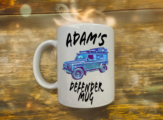 Mug with a graphic of a Land Rover Defender and text 'Adam's Defender Mug' on a wooden background
