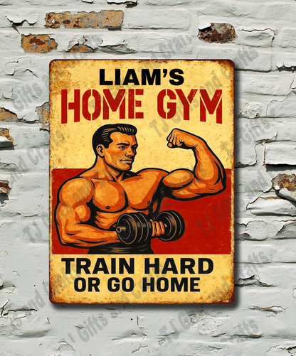 A rectangular vintage-style metal sign with a muscular man flexing dumbbells and the text 'LIAM'S HOME GYM' and 'TRAIN HARD OR GO HOME,' mounted on a distressed white brick wall.