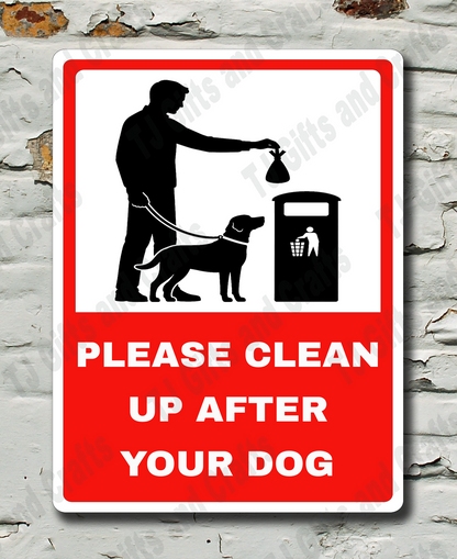 A rectangular warning sign with a red border and white center, featuring a black silhouette of a person with a dog next to a trash can, with the text 'PLEASE CLEAN UP AFTER YOUR DOG' in white on a red background. The sign is mounted on a distressed white brick wall.