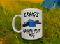 White mug with 'Craig's Rooftop Tent Mug' text and graphics on grass with a tent in the background
