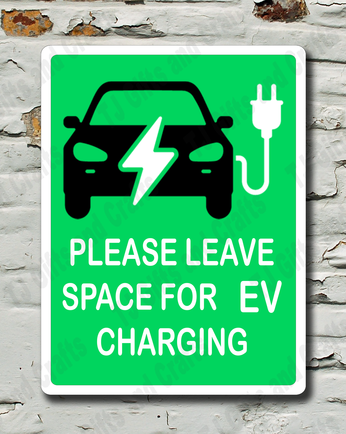 A rectangular green sign with a black car and charging plug icon, reading 'PLEASE LEAVE SPACE FOR EV CHARGING,' mounted against a distressed white brick wall.
