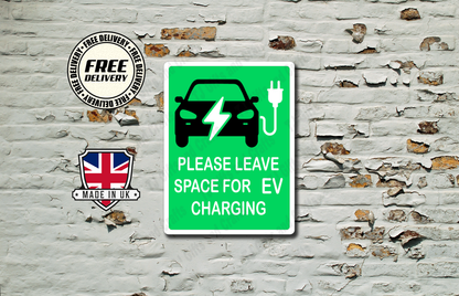 A green rectangular sign with a black electric car and charging plug icon, plus the text 'PLEASE LEAVE SPACE FOR EV CHARGING,' displayed against a distressed white brick wall. Two circular badges appear to the left reading 'FREE DELIVERY' and 'MADE IN UK.
