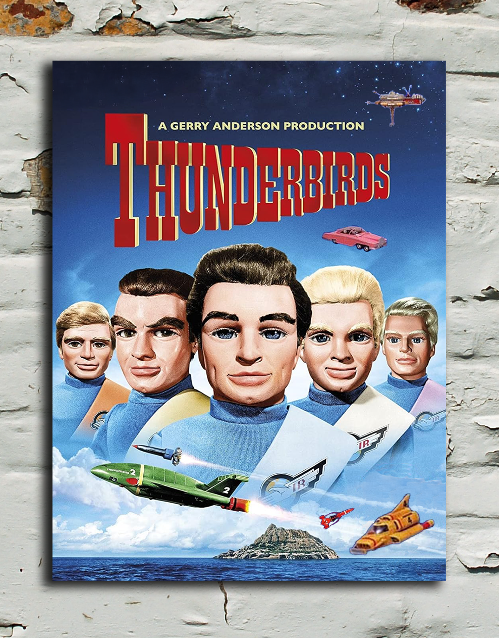 A vintage-style Thunderbirds poster mounted on a distressed white brick wall. The poster features the movie title 'Thunderbirds' in large red letters above an illustration of the crew in colorful spacesuits and a small spacecraft.