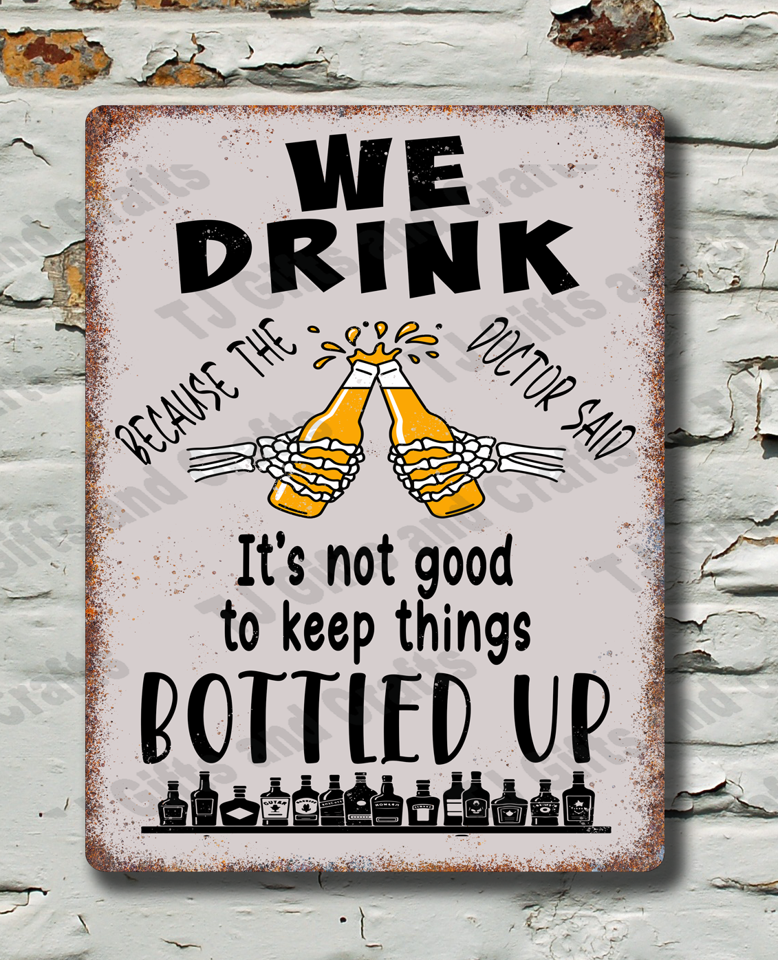 A rectangular vintage-style metal sign with a distressed white background and black text reading 'WE DRINK BECAUSE THE DOCTOR SAID It's not good to keep things BOTTLED UP,' with two clinking beer glasses in the center, displayed against a white brick wall with peeling paint.