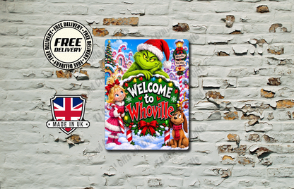 A square metal tin sign featuring a festive Christmas illustration with the text 'Welcome to Whoville' and characters resembling the Grinch, Santa, and a dog, displayed against a distressed white brick wall.